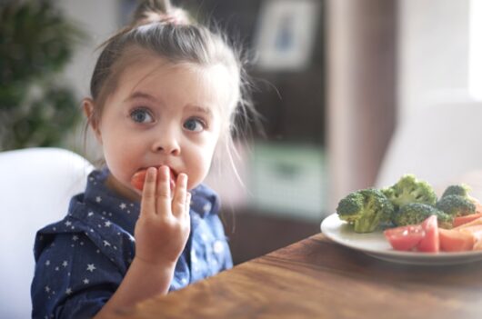 トマトとブロッコリーを食べる女の子